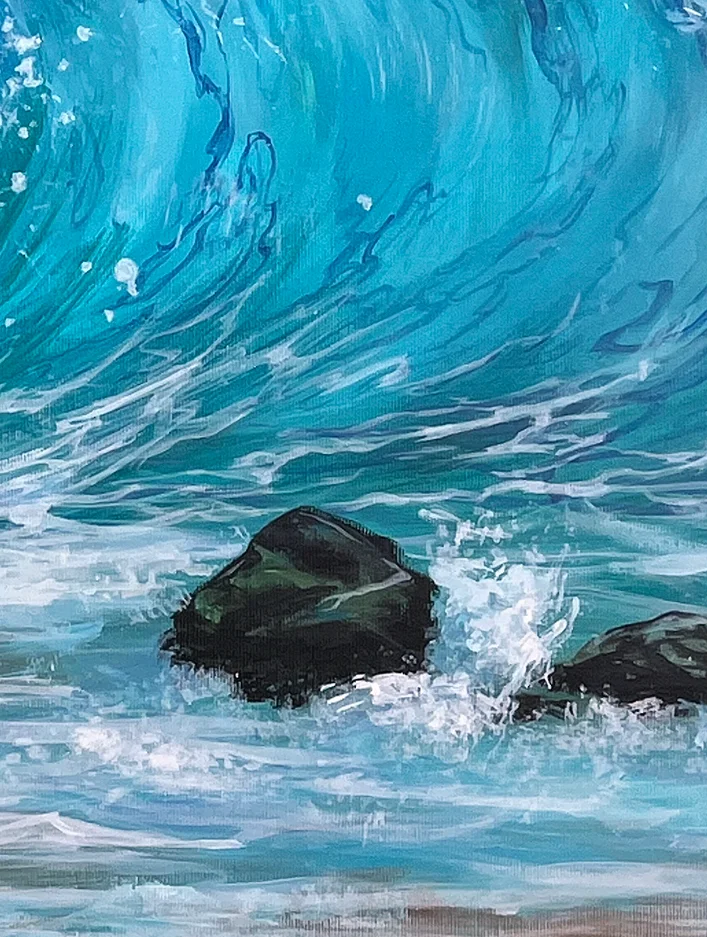 Close detail: the turquoise underside of the wave sweeping down to dark rocks in the breaking surf