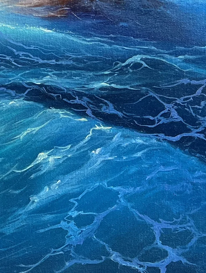 Close detail: deep blue water threaded with a pale lacework of foam, dark swell rising behind