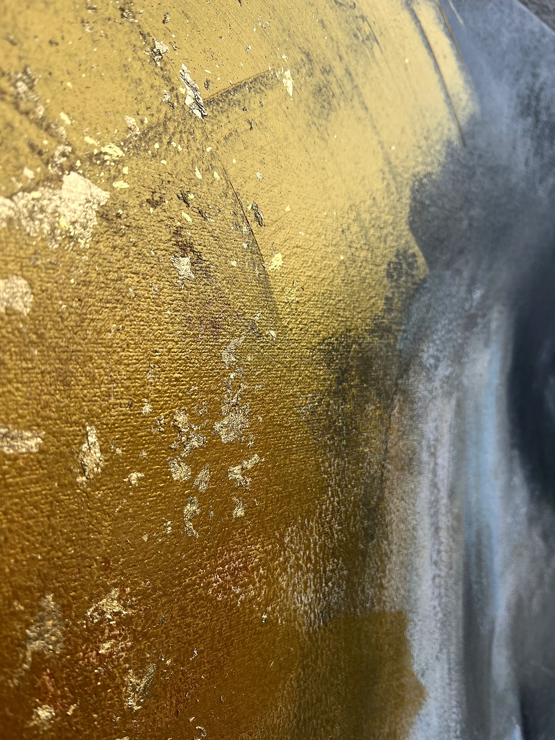 Detail of the painting Face by Natalie Streit: the textured gold ground with flakes of metal leaf, dark grey shading fading into it from above