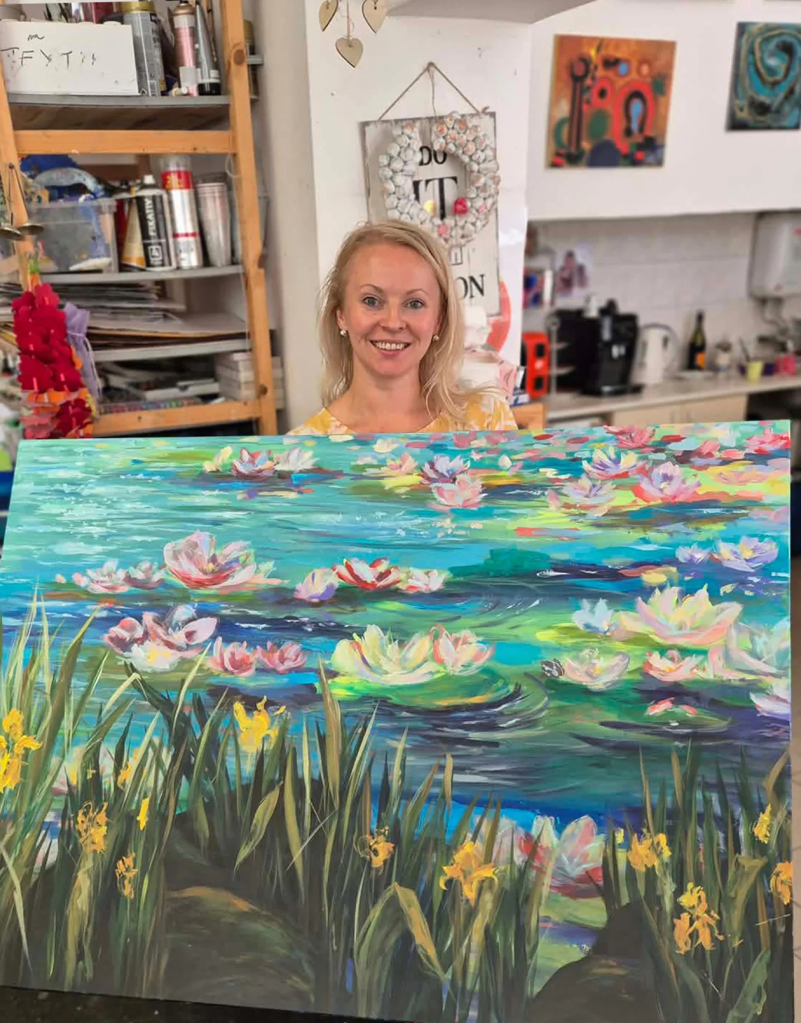 Natalie Streit in her studio, holding the finished canvas of Wild Flowers